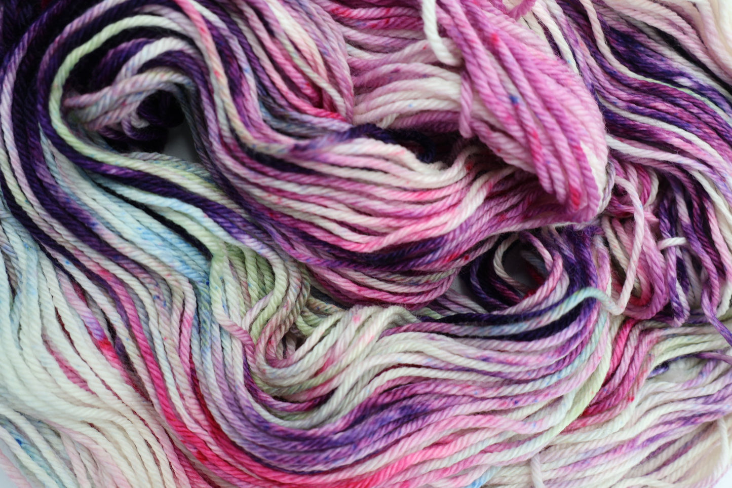 Multicolored yarn skein with shades of pink, purple, and blue.