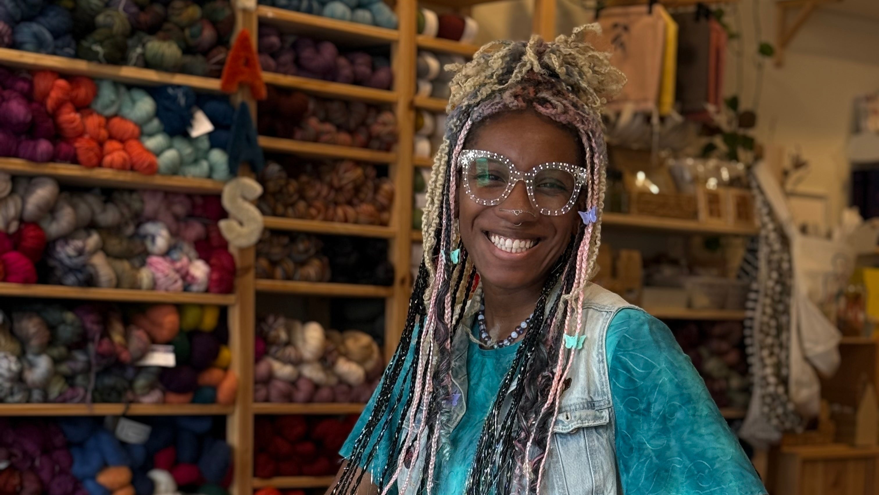 Woman in a teal dress sitting in a yarn store